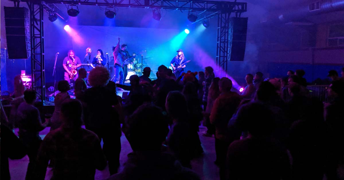 Music band playing under colored lights in front of a large crowd