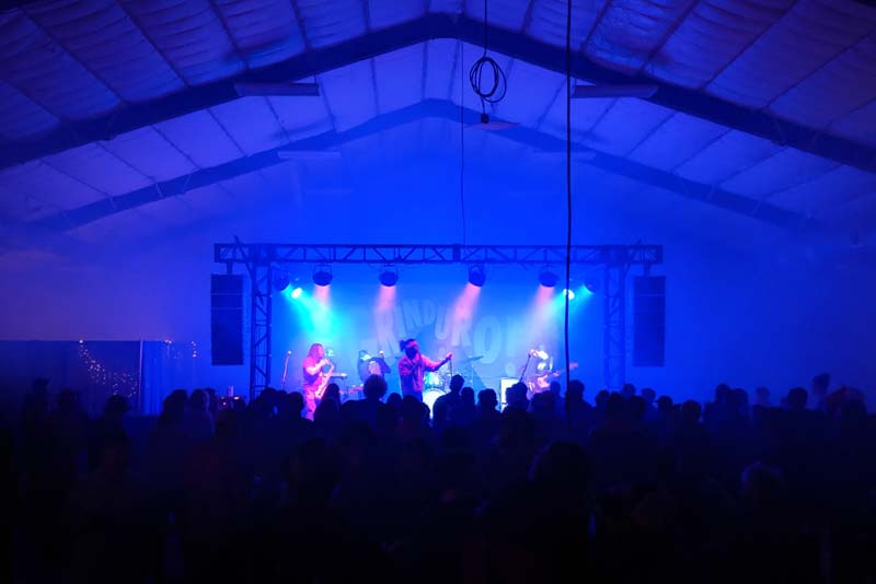 Music band playing under colored lights in front of a large crowd